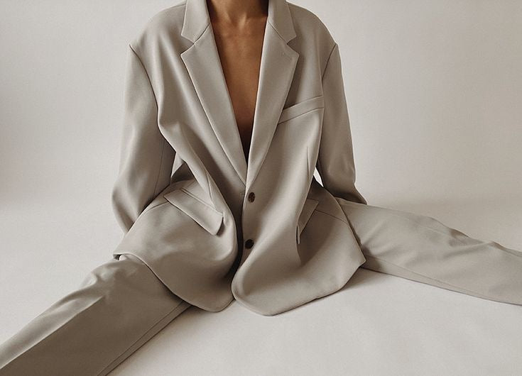 Modelis su kreminės spalvos kostiumu studijoje